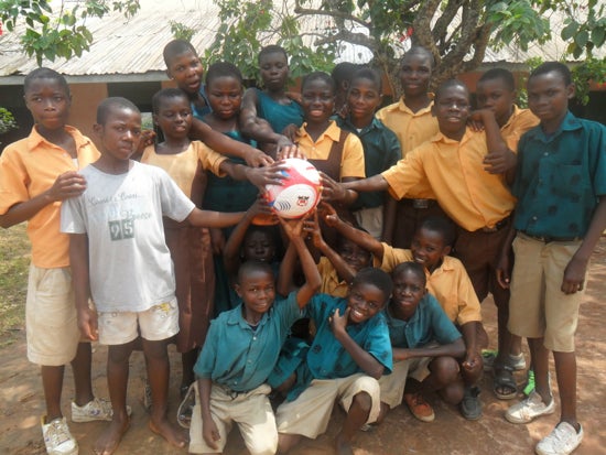 A group of students posing for the photo and touching a soccer ball
